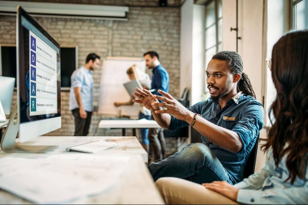 Individual gestures at computer while speaking to colleague